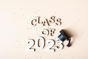 Class of 2023 concept. Wooden number 2023 with graduated cap on colored background. photo