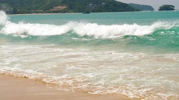 Picturesque huge powerful waves with heavy white foam roll on beach of azure ocean on sunny summer day video