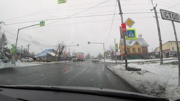 Traffic light. View from the front window of the car on the wet snowy roads of the city and the red traffic light video