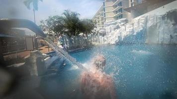 idosos cinzento cabelos homem obtendo hidroterapia dentro a piscina do uma spa hotel. cascata a partir de a chuveiro entra a piscina água video
