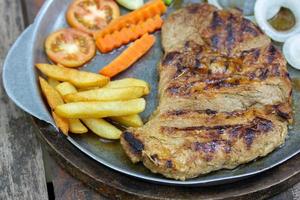 Close up of Grilled Pork Steaks and French Fries with Vegetable photo