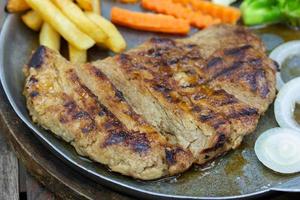 Close up of Grilled Pork Steaks and French Fries with Vegetable photo