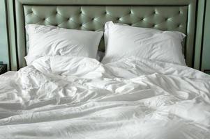 sucio blanco cama hojas y almohada en el Mañana a habitación foto