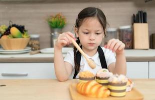 retrato de un pequeño niña en el cocina de un casa teniendo divertido jugando horneando un pan foto