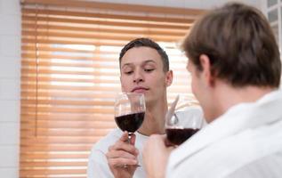 lgbt joven Pareja celebrar el día de amor Entre cada otro con multa vino en el cocina de el casa foto