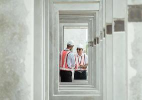 Both of construction engineers verify the constructed precast concrete wall slabs' quality. also to oversee significant construction projects in the construction zone photo