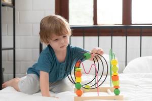 Little boy in his bedroom with a new toy purchased by his parents to help him improve his thinking skills. photo