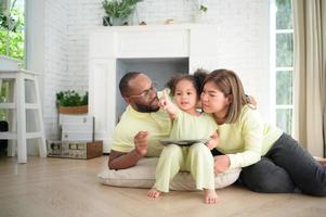 Little children play and learn things in the wide world on tablet. with parents to supervise and help in the living room of the house on vacation photo