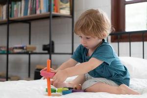 Little boy in his bedroom with a new toy purchased by his parents to help him improve his thinking skills. photo