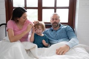 After the little boy wakes up from his nap, his father and mother engage in enjoyable activities in his bedroom. photo