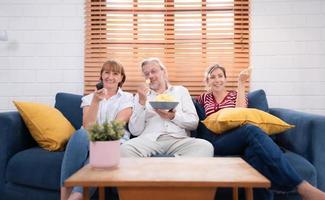 en el familia vivo habitación sofá, padre, madre y hija felizmente Visto el de familia favorito televisión espectáculo. foto