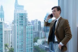 Young businessman sit and relax in the relaxation room by the window overlooking the beautiful city buildings. along with the phone to talk about business. photo