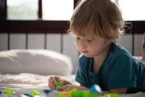 Little boy in his bedroom with a new toy purchased by his parents to help him improve his thinking skills. photo