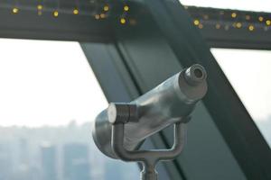 Coin-operated binoculars looking out over city , photo