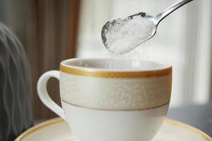 pouring white sugar in a coffee cup , photo