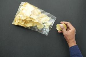 men pick potato chips from a plastic packet photo