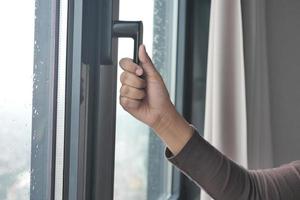 Young woman opening window in flat photo