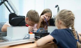 niños utilizando el mano robot tecnología, estudiantes son estudiando tecnología, cuales es uno de el vástago cursos foto