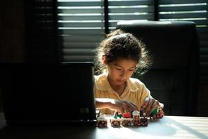 retrato de pequeño niña en el oficina habitación de casa, ellos son teniendo divertido jugando con juguete trenes foto