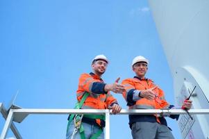 Surveyor and engineer Examine the efficiency of gigantic wind turbines that transform wind energy into electrical energy that is then used in daily life. photo