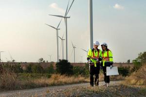 Man and female engineer stationed at the Natural Energy Wind Turbine site. with daily audit tasks of major wind turbine operations that transform wind energy into electrical electricity photo