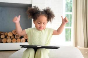 A young bright cute little girl with her trusty tablet that makes her happy and joyful. photo