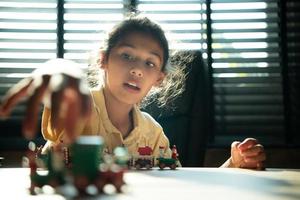 Portrait of little girl in the office room of house, They are having fun playing with toy trains photo