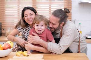 Mom and dad in the kitchen of the house with their small children. Have a good time making dinner together. photo