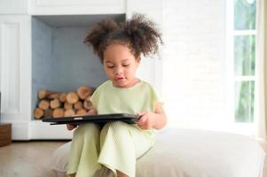 A young bright cute little girl with her trusty tablet that makes her happy and joyful. photo