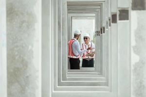 Both of construction engineers verify the constructed precast concrete wall slabs' quality. also to oversee significant construction projects in the construction zone photo