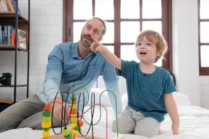 Father with little boy have fun playing with your new toys in the bedroom together. Toys that enhance children's thinking skills. photo