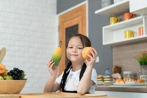 retrato de un pequeño niña en el cocina de un casa teniendo divertido jugando con Fruta juguete y batería de cocina foto
