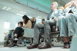 Passengers listen to flight attendants demonstrate how to use safety equipment. photo