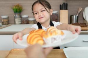 Portrait of a little girl in the kitchen of a house having fun playing baking bread photo