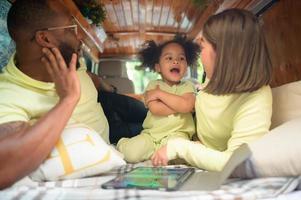 el espalda de un blanco clásico camioneta, pequeño niños jugar y aprender acerca de el mundo en su tableta con padres tomando cuidado de Ayudar. foto