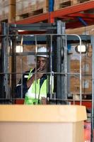 Worker in auto parts warehouse use a forklift to work to bring the box of auto parts into the storage shelf of the warehouse waiting for delivery to the car assembly line photo