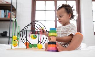 Little girl in his bedroom with a new toy purchased by his parents to help him improve his thinking skills. photo