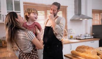 Mom and dad in the kitchen of the house with their small children. Have a good time making dinner together. photo