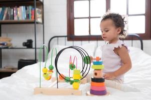 Little girl in his bedroom with a new toy purchased by his parents to help him improve his thinking skills. photo