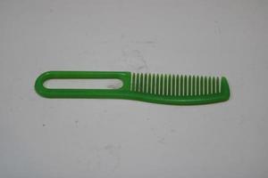 photo of a green hair comb made of plastic with a white background