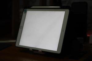 Photo of an empty tablet with white screen on the table