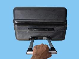 top view of hand holding suitcase isolated on blue background photo
