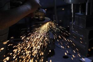 Metal treatment. Grinding of steel. Sparks from disk. Work in workshop. photo