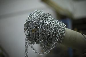 Steel chain wound on stick. High strength steel chain. Industrial item. Links of silver color. photo