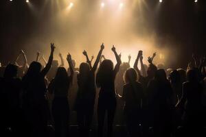 Black silhouette of a huge crowd of cheering people in front of a rock stage with soft bokeh lights created with technology. photo