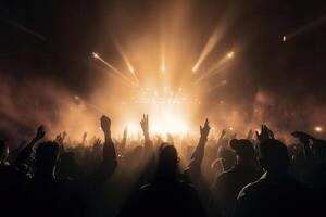 Black silhouette of a huge crowd of cheering people in front of a rock stage with soft bokeh lights created with technology. photo