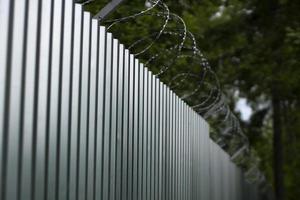 Steel fence with barbed wire. Fence around plant. Private territory. Metal profile. Dangerous wire. photo