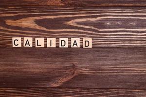 Calidad, quality spanish word, lettering on wooden background photo