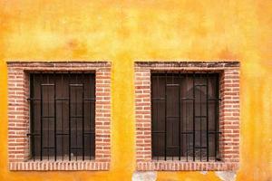 Two barred windows with colorful paed mexican background photo