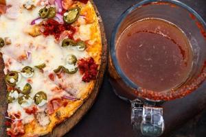 mexicano Pizza con un michelada bebida con cerveza y clamato en el lado. foto